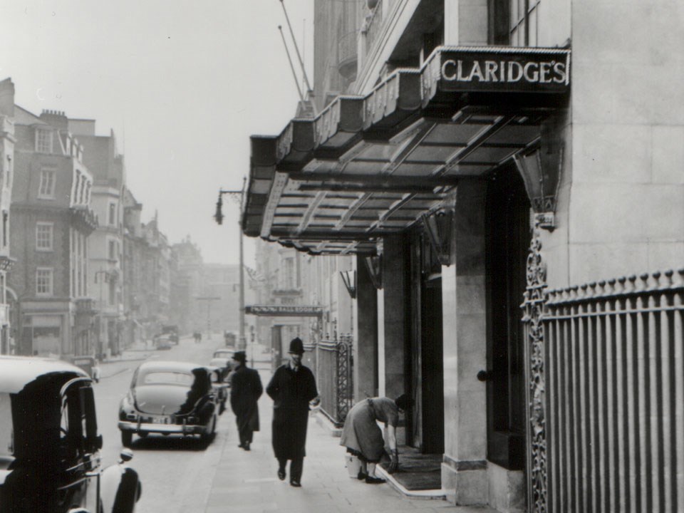 A black and white photo in front of Claridge's Hotel and the passers-by at that time as part of history.