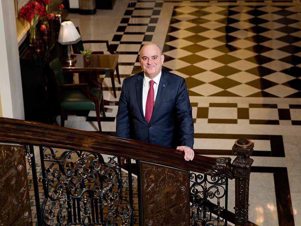 Portrait of Alex Bakirtzidis, director of private visits and embassy relations, standing on the steps of Claridge's.