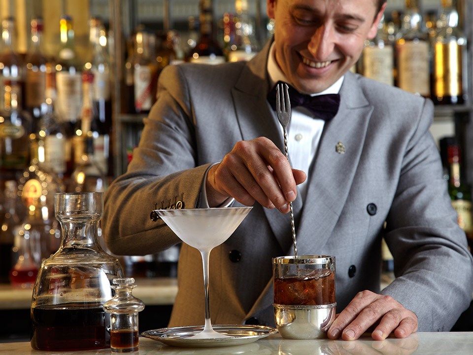 Denis Broci smilingly mixing the drink he is preparing for a cocktail at Claridge's Bar.