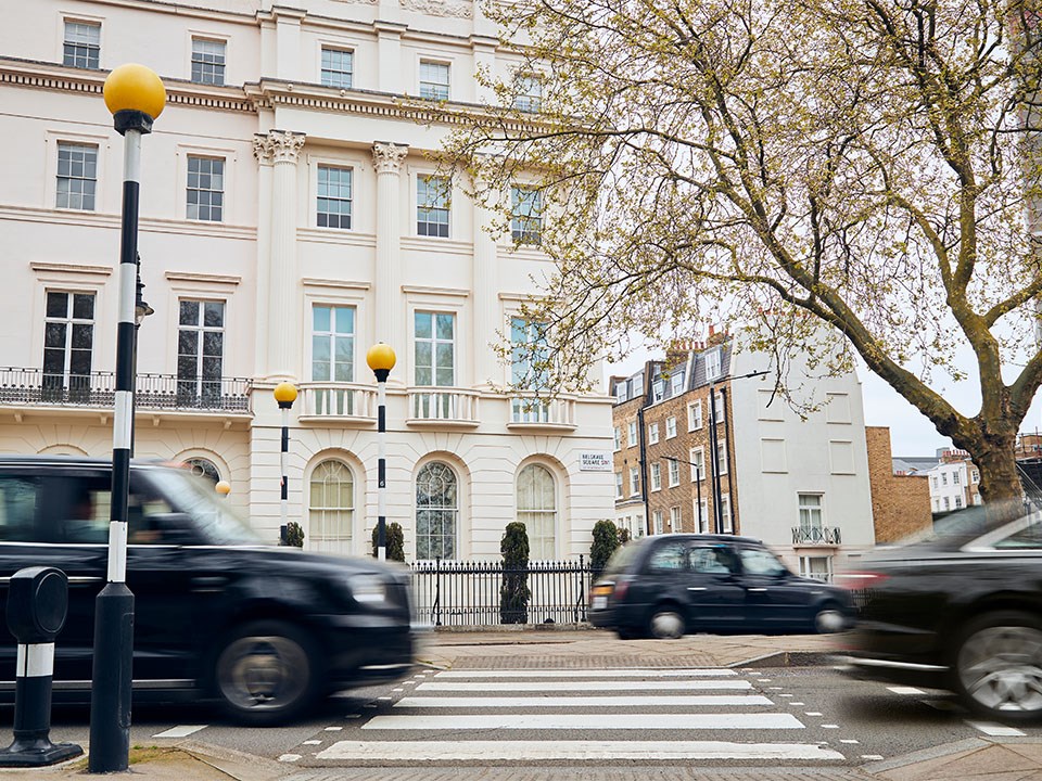 View of crossing and white residential buildings in London, with black taxis