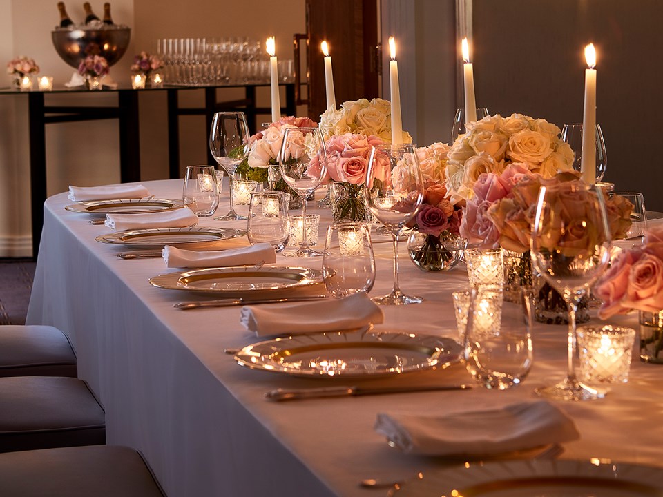 A view of the candles and flower arrangements on the set dining table, in a romantic and warm atmosphere.
