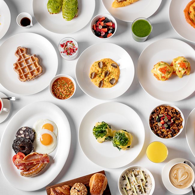 A birds eye of view of breakfast at Claridge's Restaurant. Lots of plates of breakfast are on a table - eggs benedict, avocado toast, muesli are displayed.