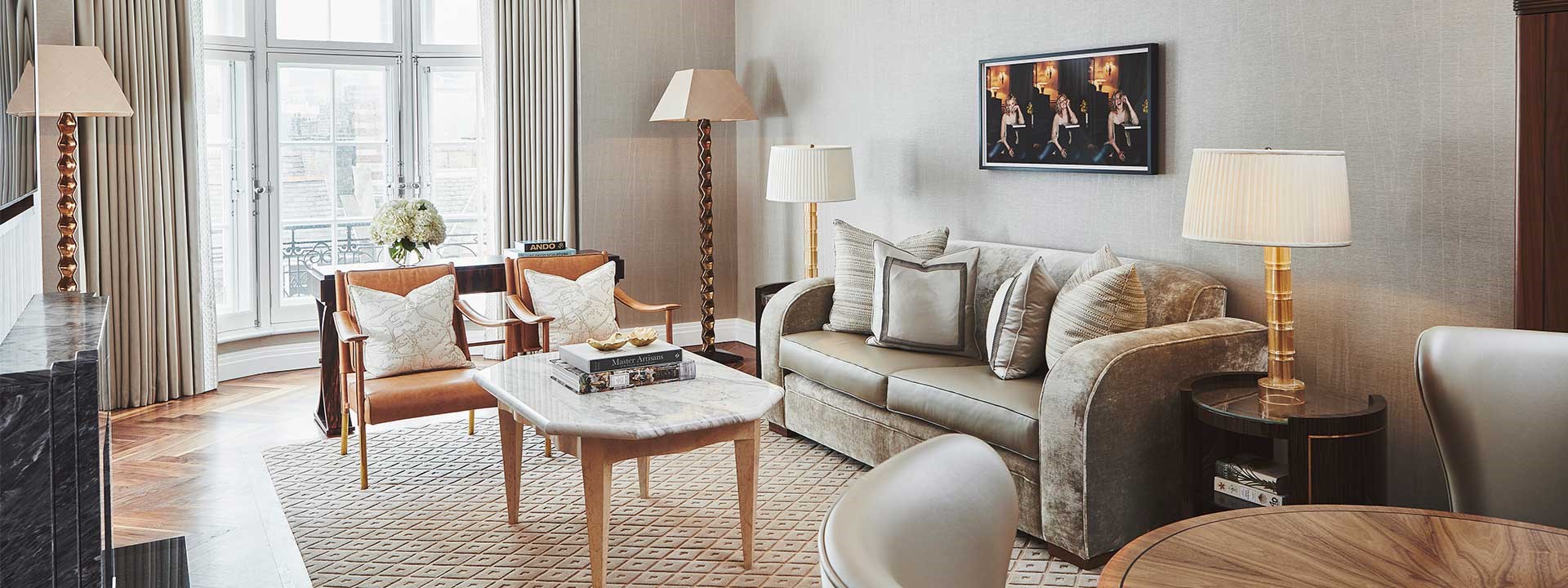 A sofa made of luxurious materials, armchairs, and lamps in the sitting room from Claridge's Terrace Suite.