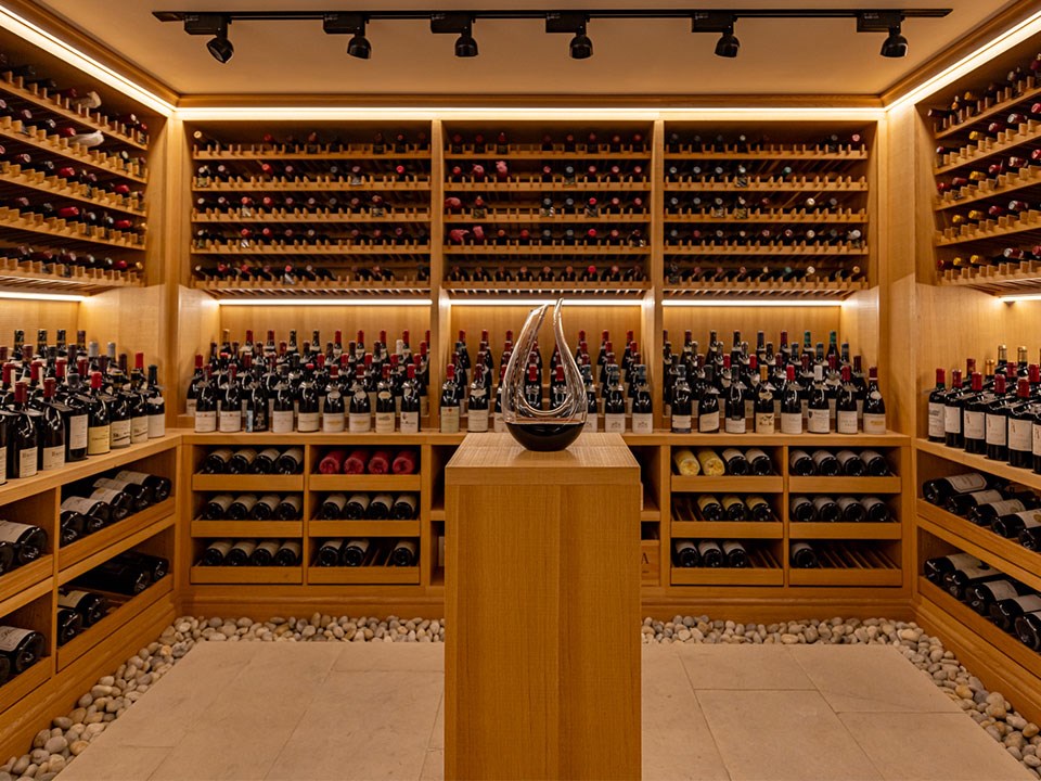 A collection of wine and champagne in the background, with a decanter in the middle at Claridge's Wine Cellar.