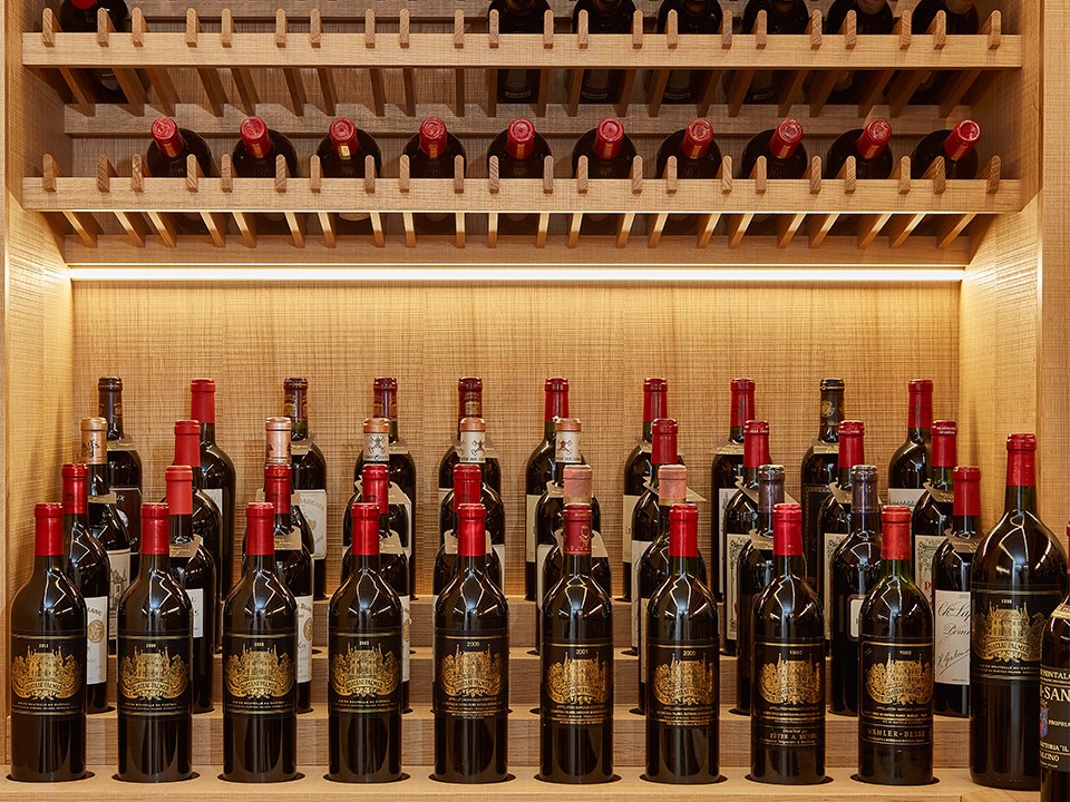 A display of stacked wine bottles, on a shelf, located in the wine cellar of The Claridge's.
