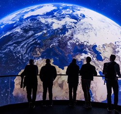 5 people standing in front of a screen showing the earth