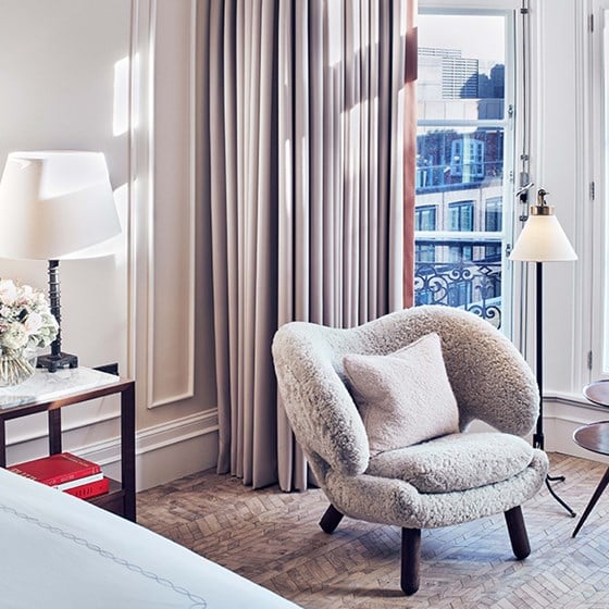 A view of a comfortable armchair in an elegant interior from Claridge's, with lamps and designer elements in the background.