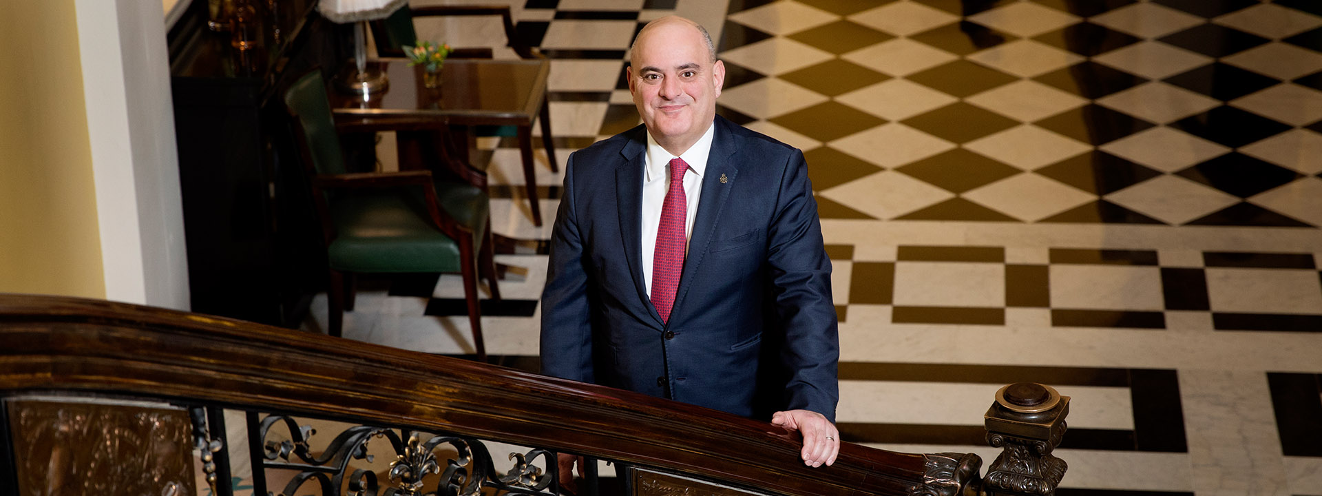 Portrait of Alex Bakirtzidis, director of private visits and embassy relations, standing on the steps of Claridge's.