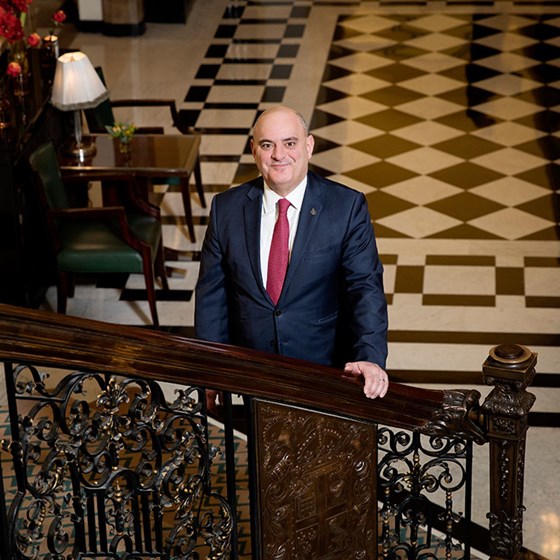 Portrait of Alex Bakirtzidis, director of private visits and embassy relations, standing on the steps of Claridge's.