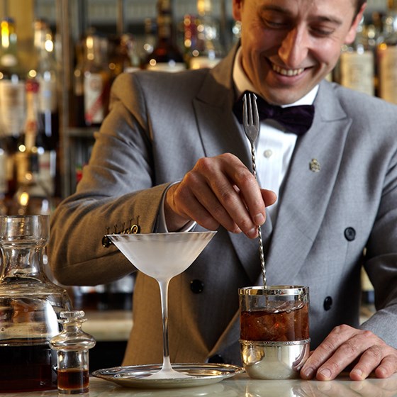 Denis Broci smilingly mixing the drink he is preparing for a cocktail at Claridge's Bar.