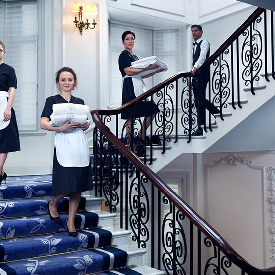Smiling workers who sweep the stairs at Claridge's Hotel and carry towels to guest rooms.
