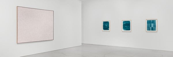 Minimalist white gallery interior featuring abstract artworks on walls, polished concrete floor, and ceiling-mounted track lighting.