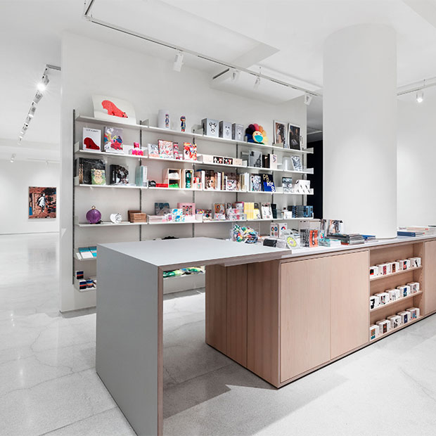 Contemporary gallery bookshop with minimalist shelving, curated art books, and a central display counter.