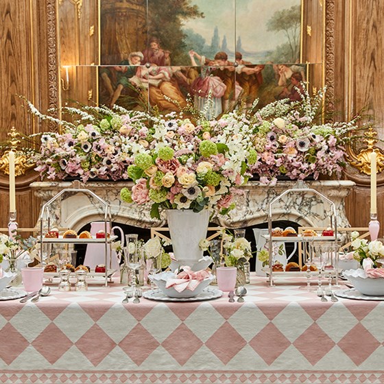 Table set up with pink flowers and tablecloth.