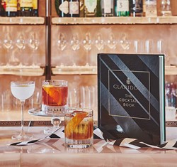 Claridge's cocktail book with three cocktails poured.