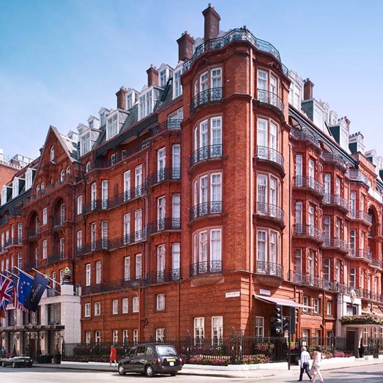 Exterior view of the magnificent building of Claridge's Hotel, with passers-by and cars in front.