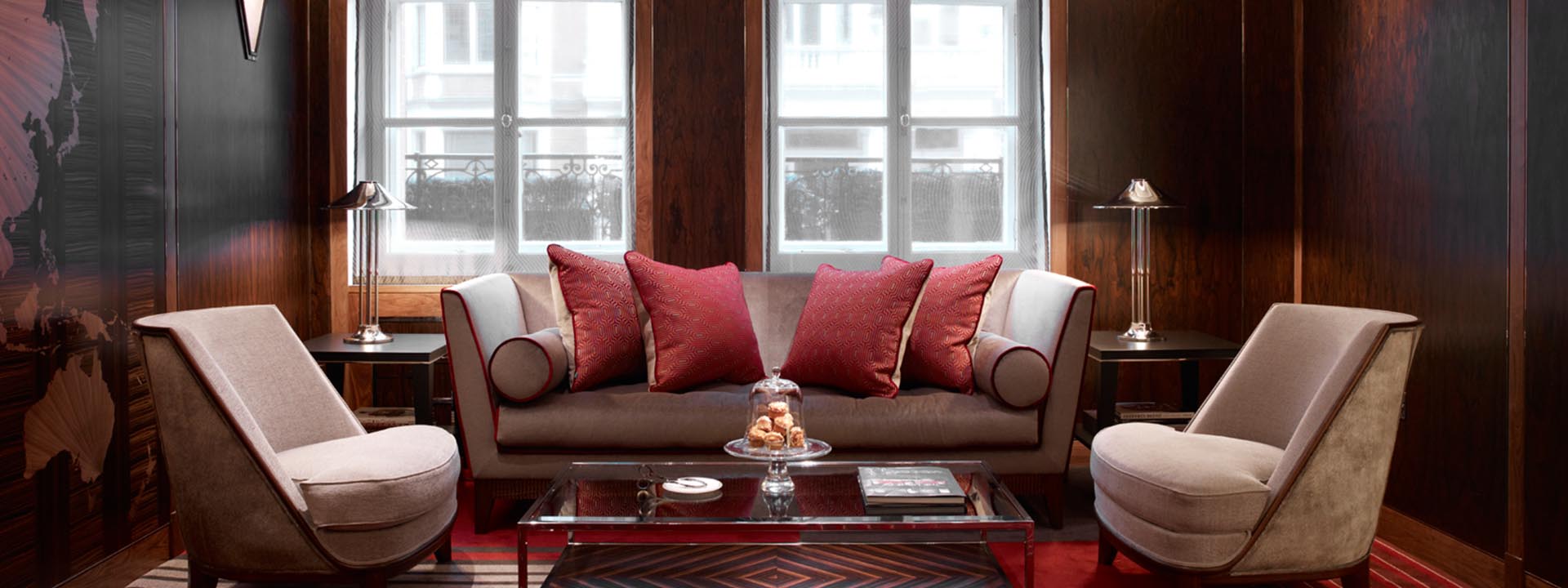 A view of Claridge's Map Room with a comfortable sofa with two armchairs in shades of red.