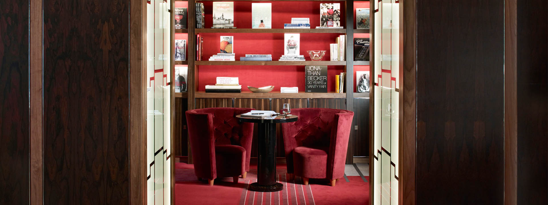 Intimate and peaceful space in Claridge's Map Room with comfortable and dark red armchairs.