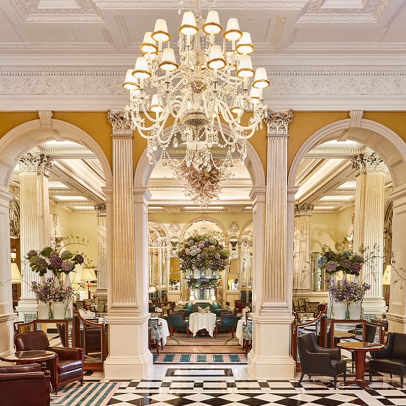 Elegant private dining room with a long flower-adorned table, mirrored walls, and Art Deco mural panels.