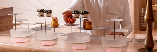 Pastry chef Thibault Hauchard carefully arranges delicate afternoon tea pastries on minimalist tiered stands at a marble counter in The Painter’s Room.