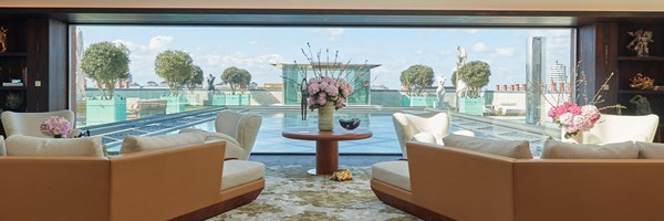 Cream sofas looking out to water feature and glass piano pavilion on rooftop of the Penthouse