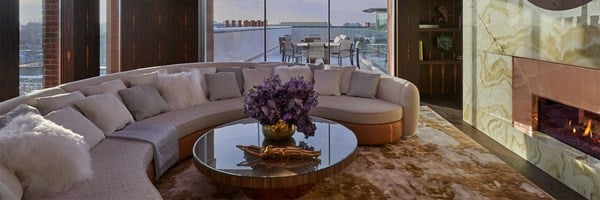 crescent shaped sofa around a coffee table, featuring a vase of purple flowers.