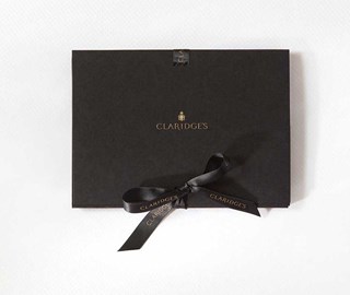 Presentation of a luxurious gift voucher to experience Claridge's, with an elegant black bow.