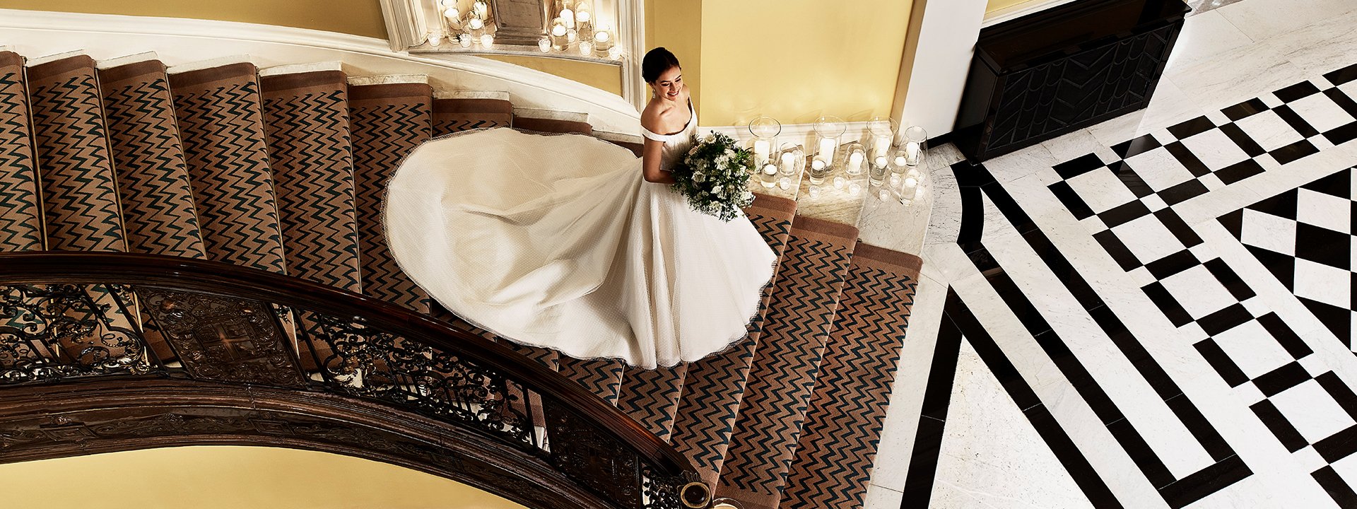 A beautiful and smiling bride with a bouquet in her hands going down the luxurious stairs.