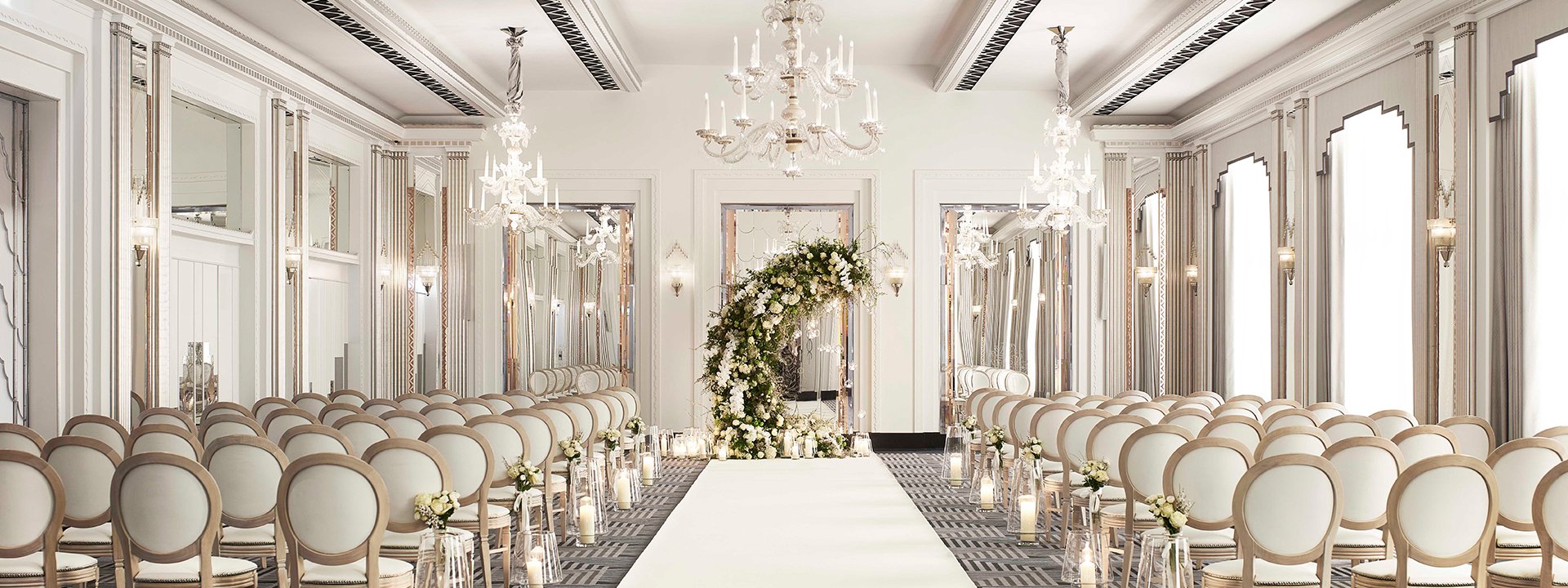 A luxurious space for a wedding in beige and champagne colours, with lots of comfortable chairs decorated with flowers.