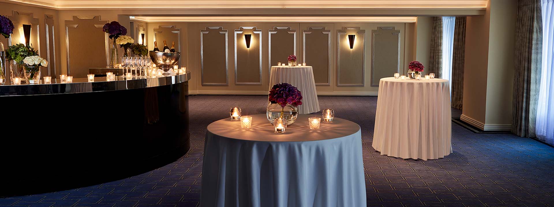 A view of part of the Clarence Room, in Art Deco design, includes a bar and tables enriched with flowers.