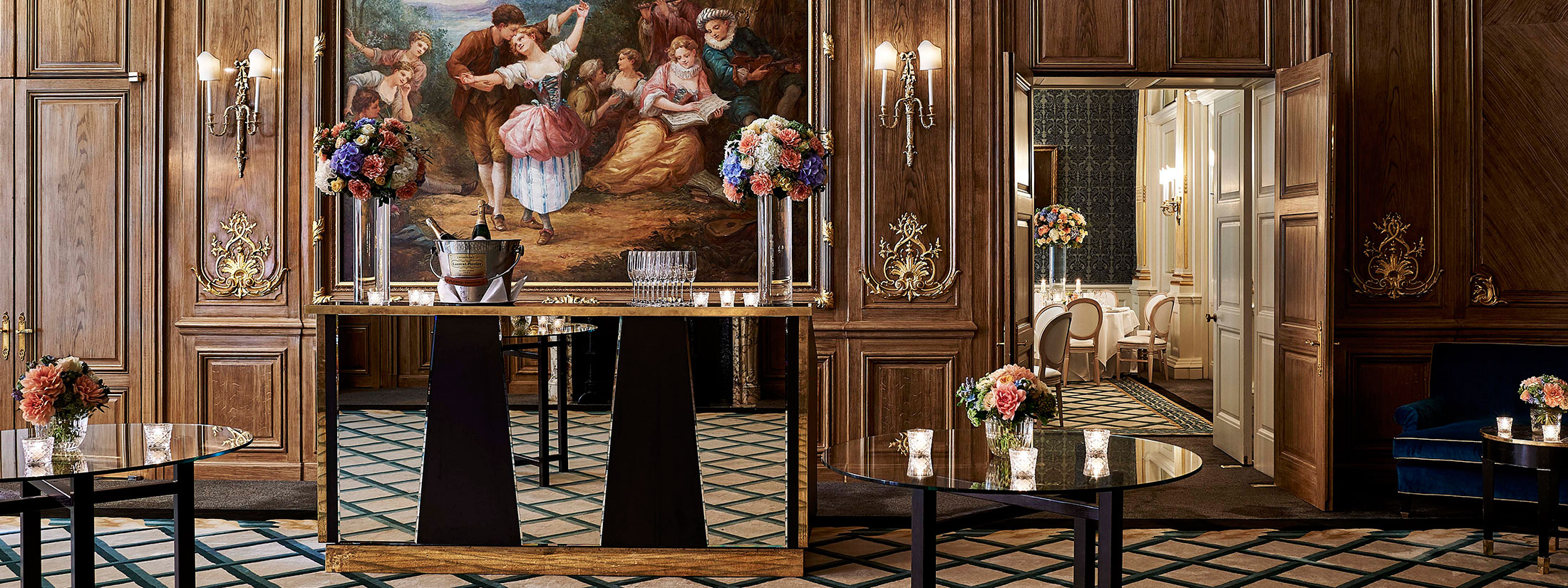 Bar setting in warmer tones, in front of a mural of a dancing couple, in the French Salon.