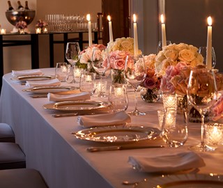 A view of the candles and flower arrangements on the set dining table, in a romantic and warm atmosphere.