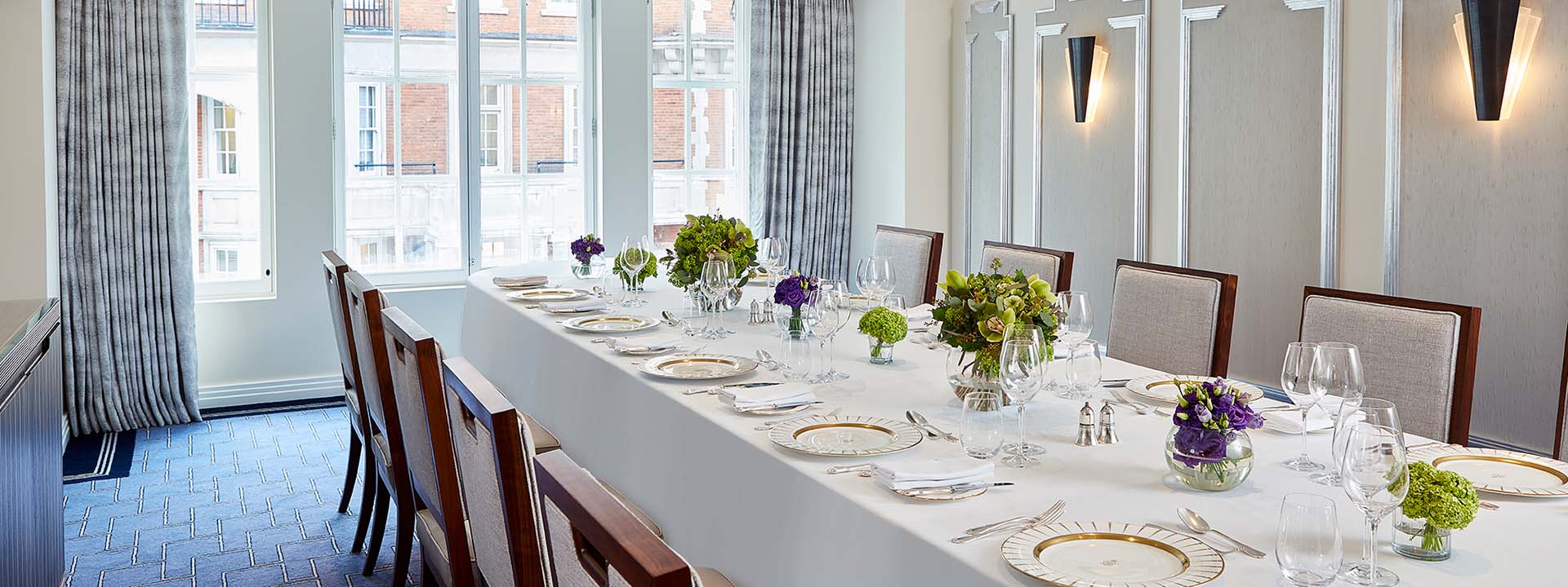 A view of the table set with floral arrangements, plates, and lots of natural daylight in the Windsor Room.