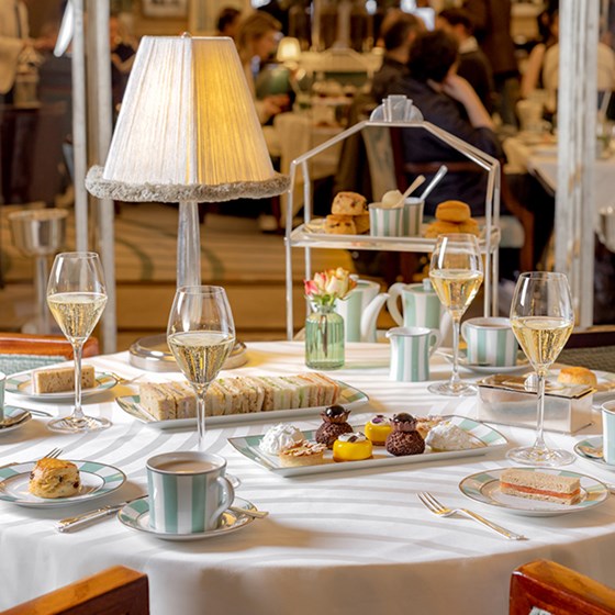 A selection of cakes and finger sandwiches with champagne glasses at The Foyer and Reading Room.