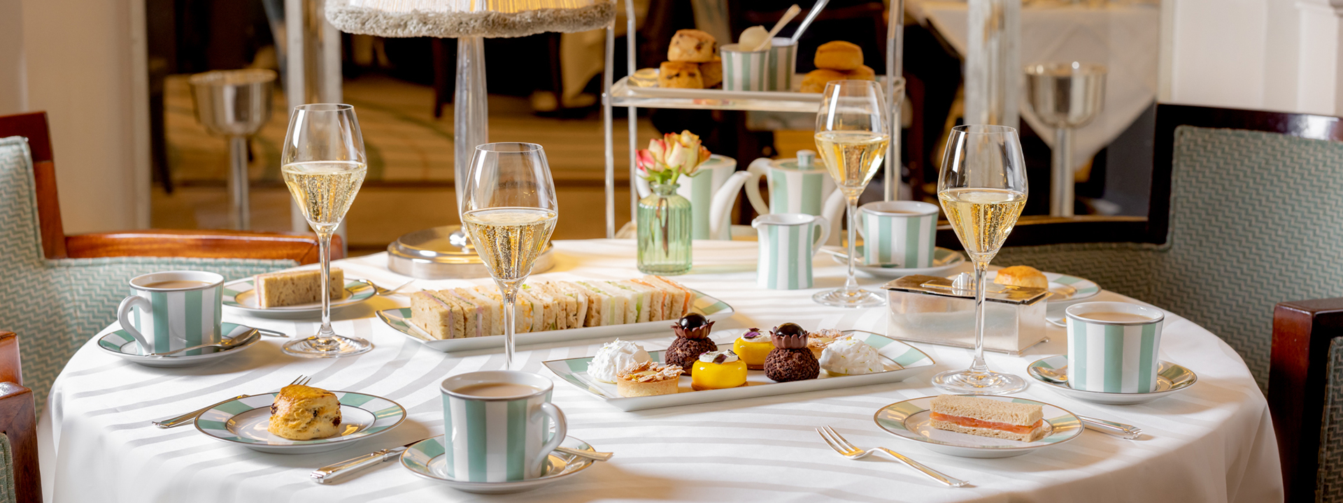 A selection of cakes and finger sandwiches with champagne glasses at The Foyer and Reading Room.