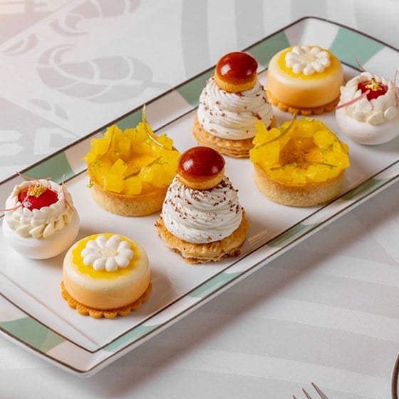 afternoon tea pastries placed on a serving plate, with choux buns, tarts and mousse creations all spring inspired