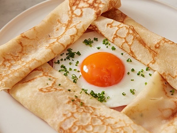 A ham and cheese crepe with an egg in the middle