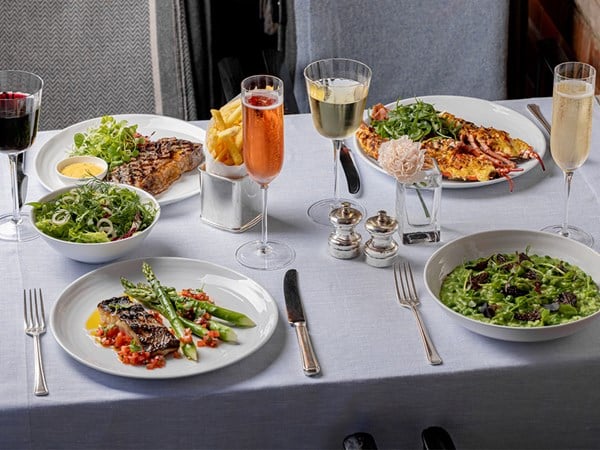 Claridge's Bar terrace with four Mediterranean dishes, with 2 glasses of champagne, 2 glasses of wine, salt & pepper and a single flower in a vase.