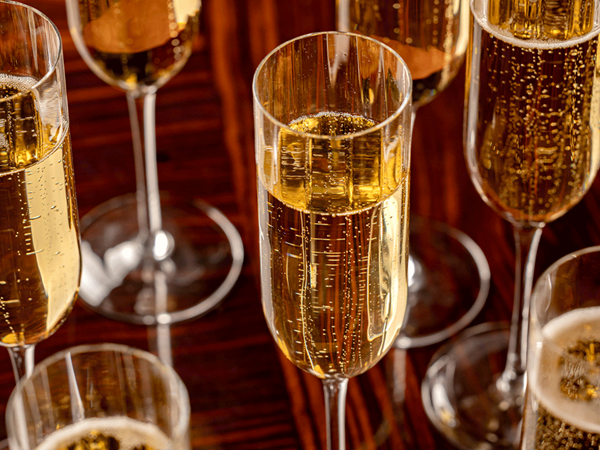 Close-up of champagne flutes filled with sparkling wine on a polished wooden table.