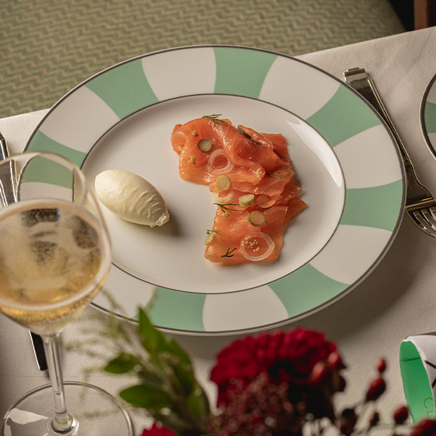 Slices of smoked salmon garnished with dill and pickled vegetables, with a quenelle of cream.