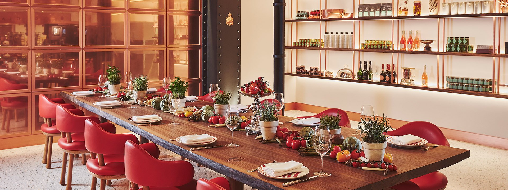A decorated table with vegetables and plates, red chairs, and a space designed for a masterclass at L'Epicerie.