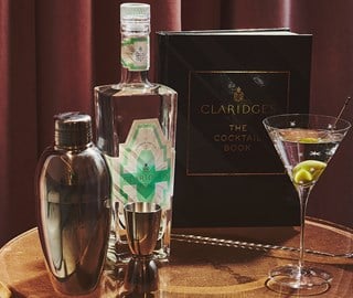 Presentation of Claridge's Gin, Cocktail Book, shaker, and martini glass with drink and olive.