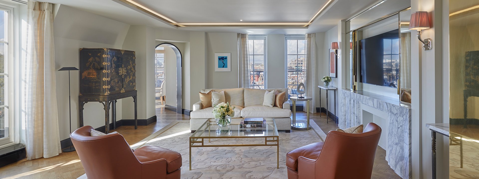 Mayfair Pavilion Suite at Claridge's - lounge with sofa, armchairs, coffee table and TV on the wall.