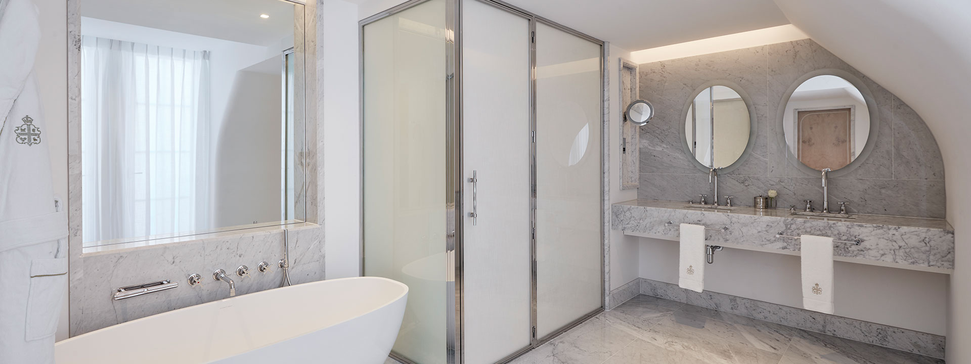 Marble bathroom with heated mirrors, double sinks, and walk-in shower in Claridge's Balcony Room.