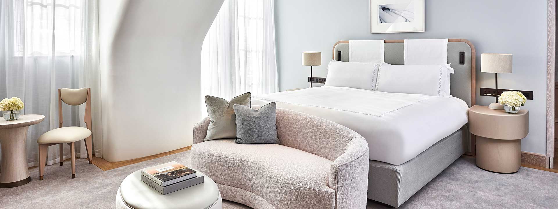 A comfortable bed and sofa in Claridge's Balcony Room, an interior with neutral colour palettes and classic design elements.