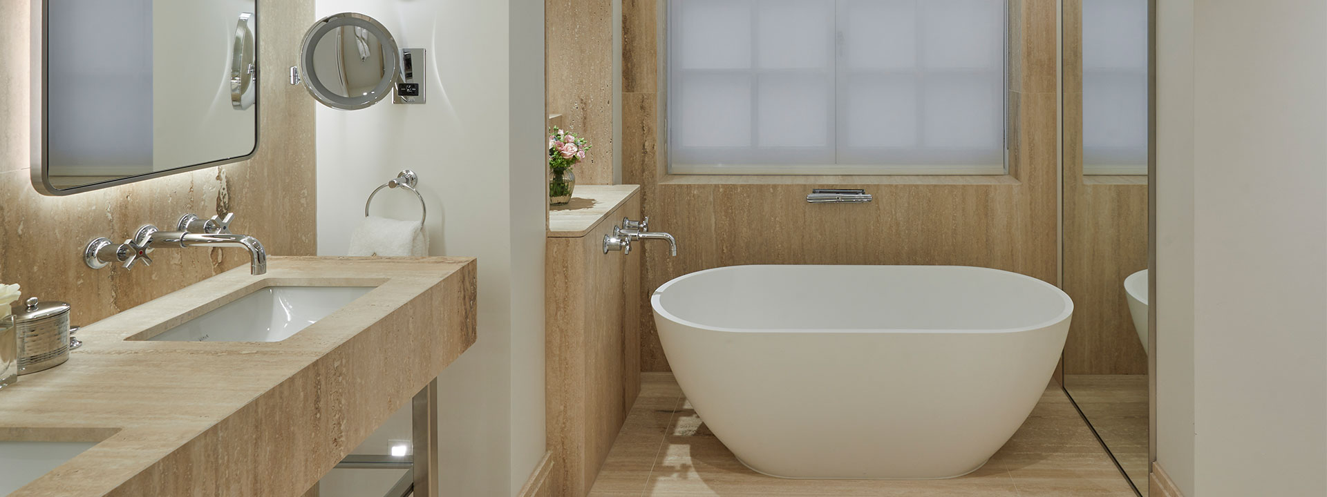 A modern bathroom, gently lit, with a large bathtub in an interior design of neutral tones for complete enjoyment.