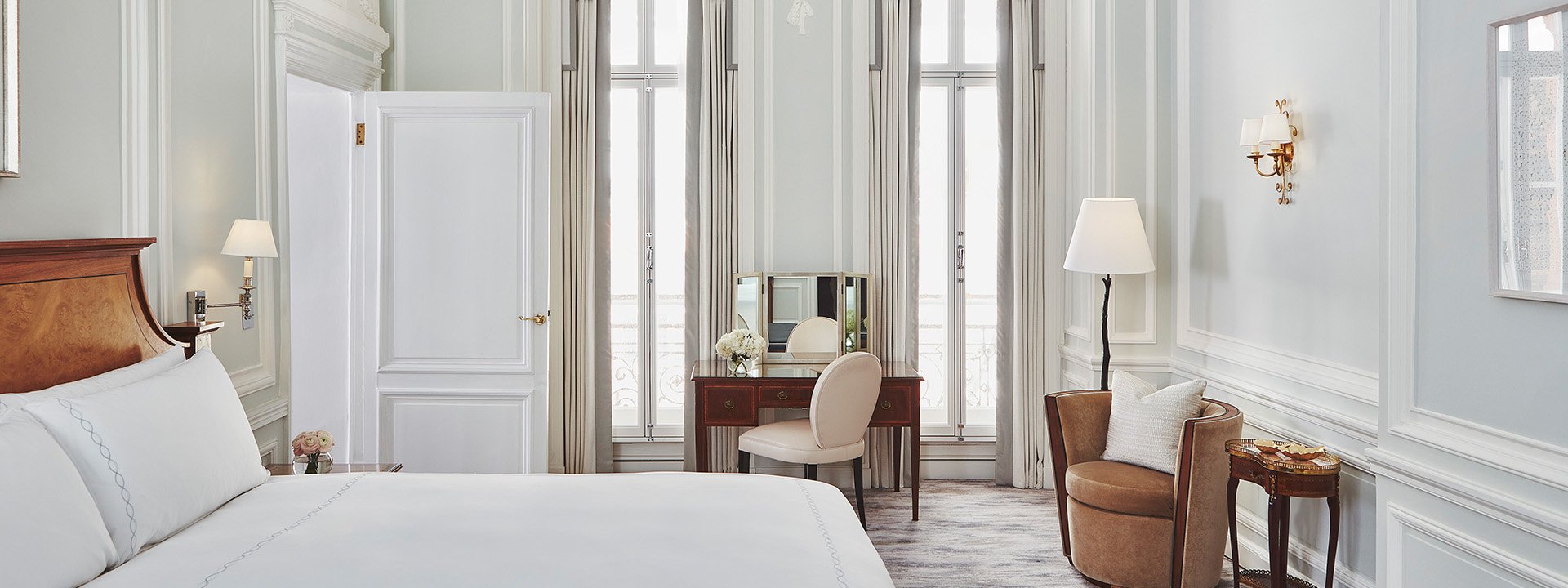 A view of the dressing table in a bedroom from Claridge's Suite, along with a comfortable bed and armchair.