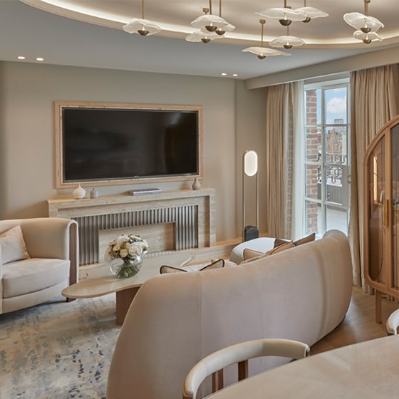 Living area of Claridge's Terrace Suite with brown sofa, hanging art and large TV