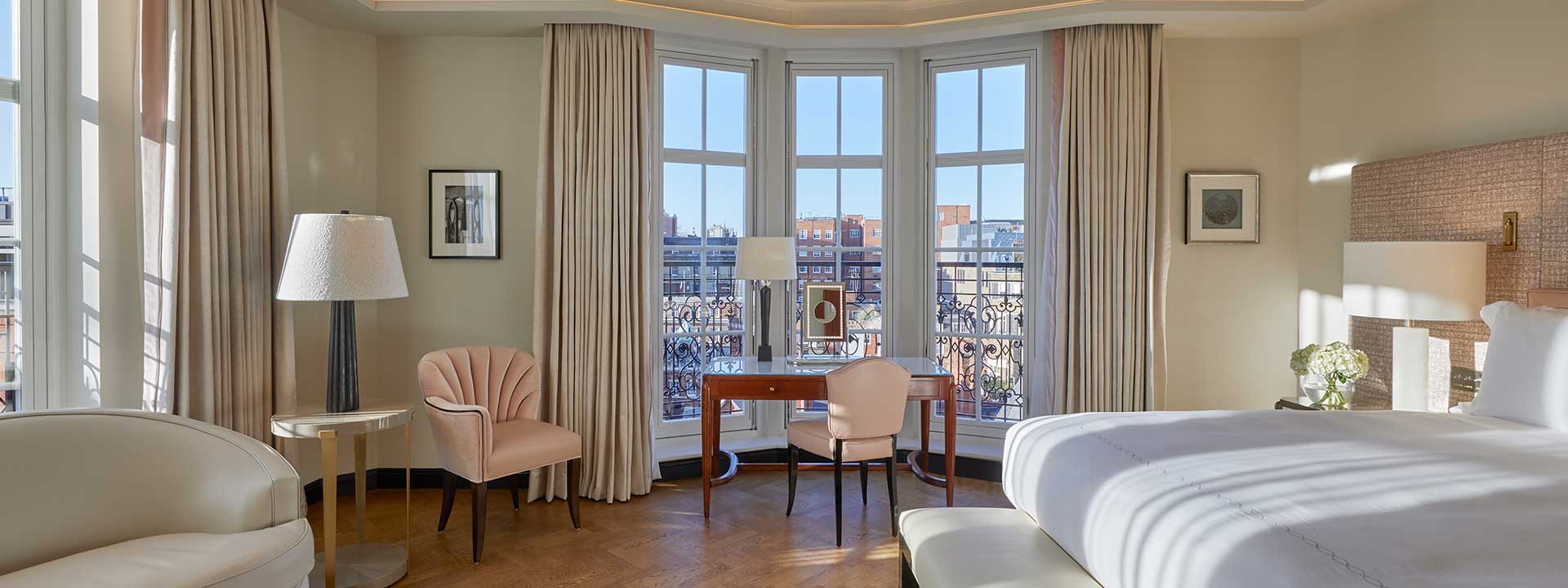 A view of the luxurious business table and pink chairs in the bedroom in the Corner Terrace Suite.