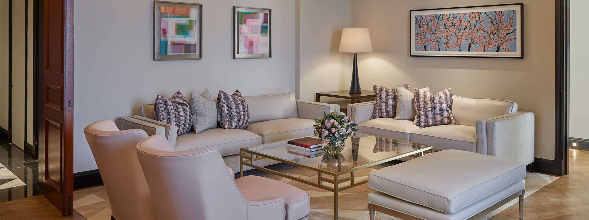 Pastel-coloured sofas and armchairs around the table, in the luxurious Sitting Room in the Corner Terrace Suite.